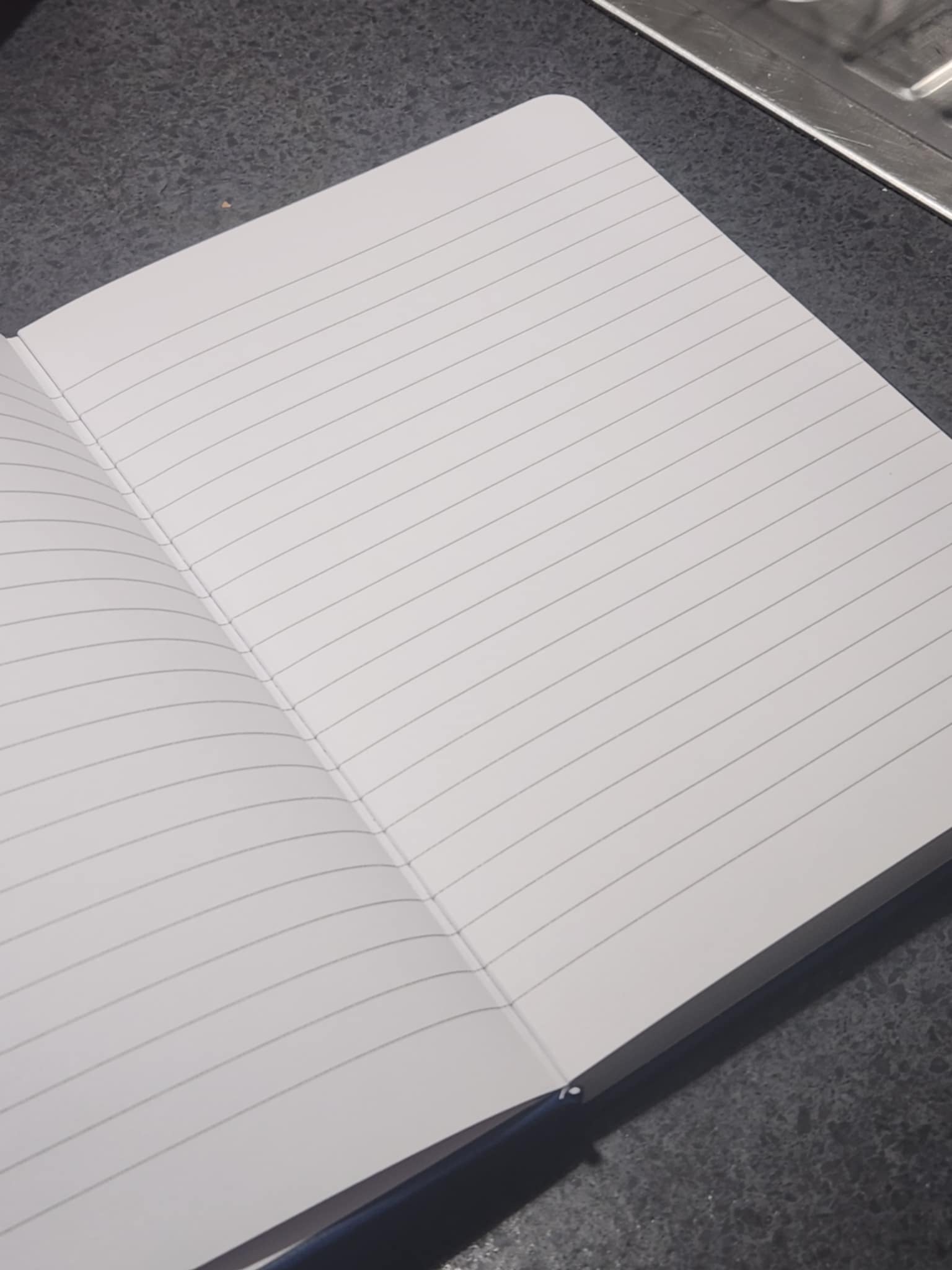 Open notebook with lined pages on a dark surface
