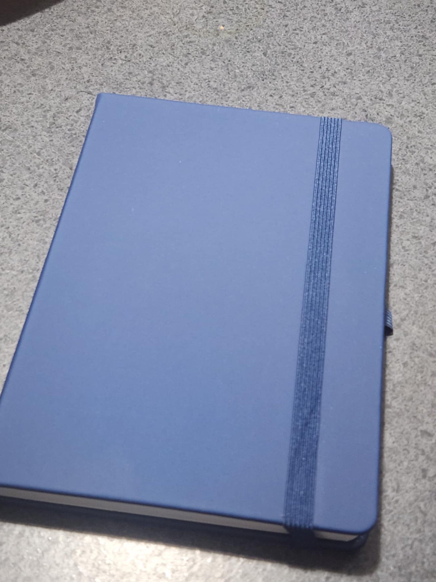 Blue notebook with a strap on a gray surface