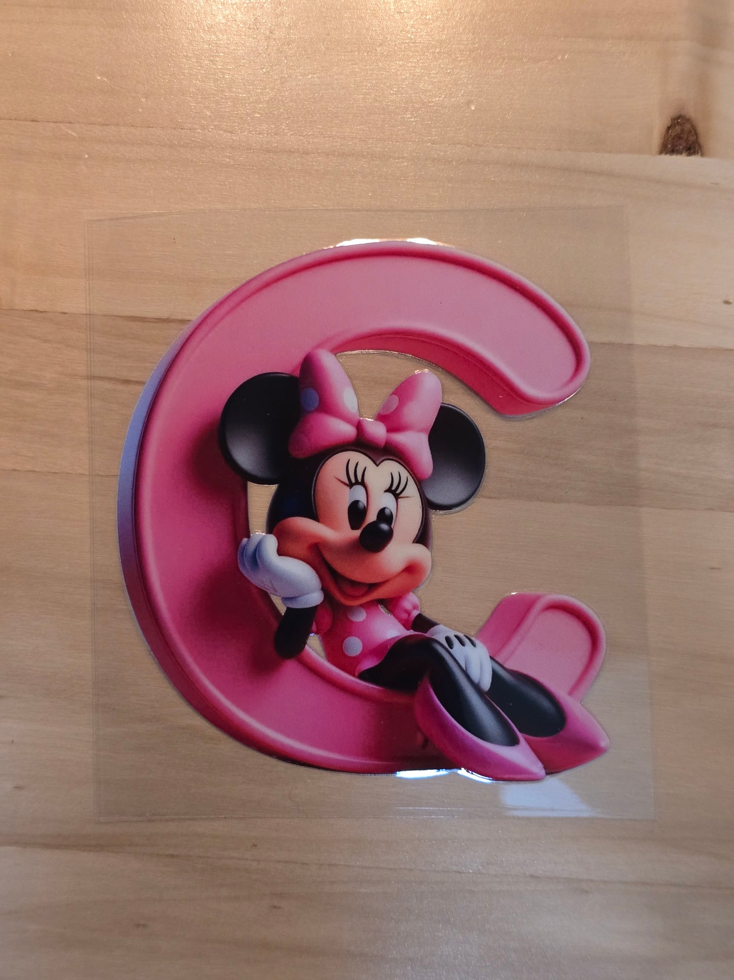 Letter C with Minnie Mouse sitting in the curve of the pink C